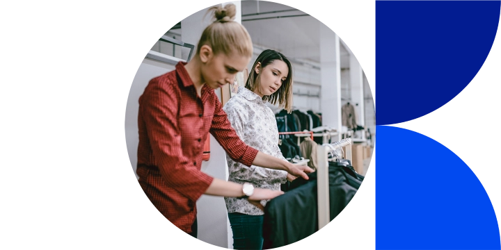 Two women inspecting blazers on a hanging rack