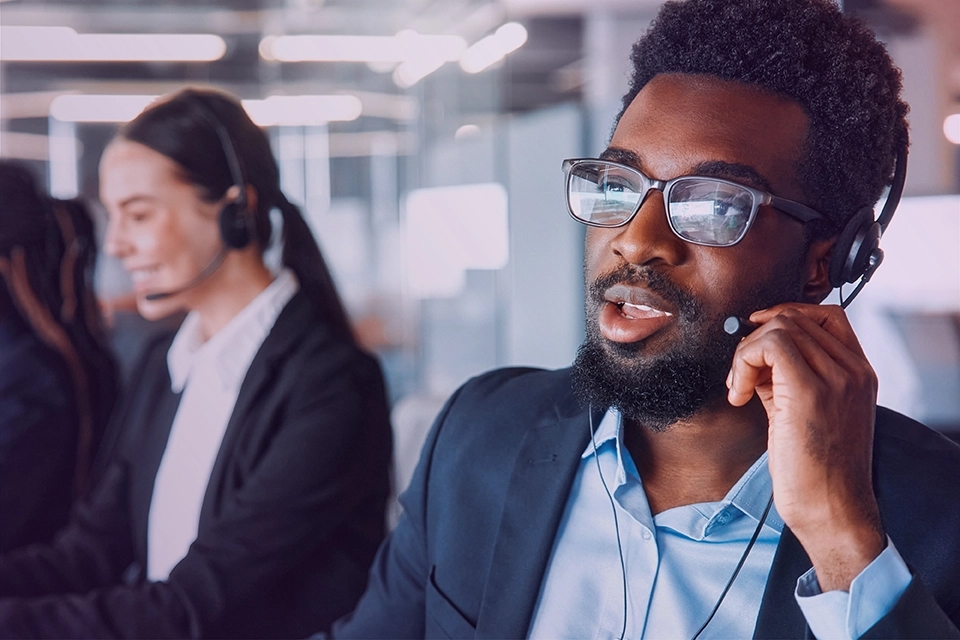 A CGS Call Center Employee at his work station, talking into a headset.